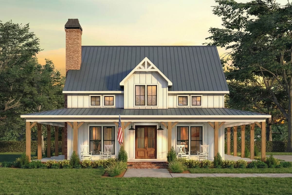 A farmhouse with white siding, a metal roof, and a covered porch. The porch features rocking chairs and a small American flag hanging nearby.