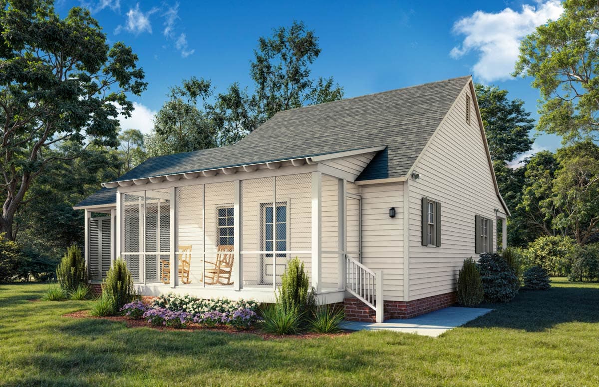 A cream-colored cottage with a screened porch and rocking chairs. The house is surrounded by green grass, flowering bushes, and trees under a blue sky.