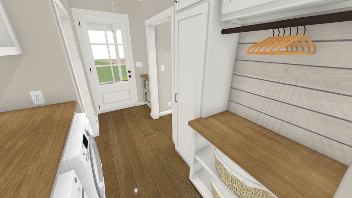 A laundry room with hardwood floors and white cabinetry. A washer and dryer are visible, along with a bench and hangers.