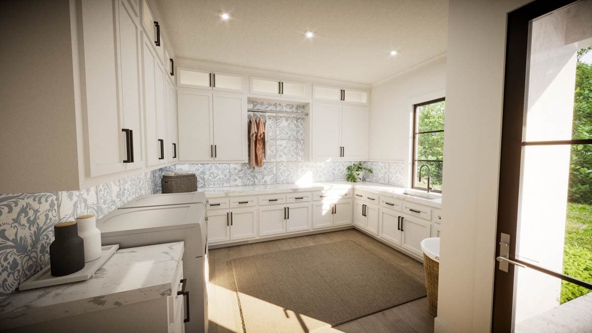 Spacious, modern laundry room with white cabinets, decorative tile backsplash, and a large window overlooking greenery.