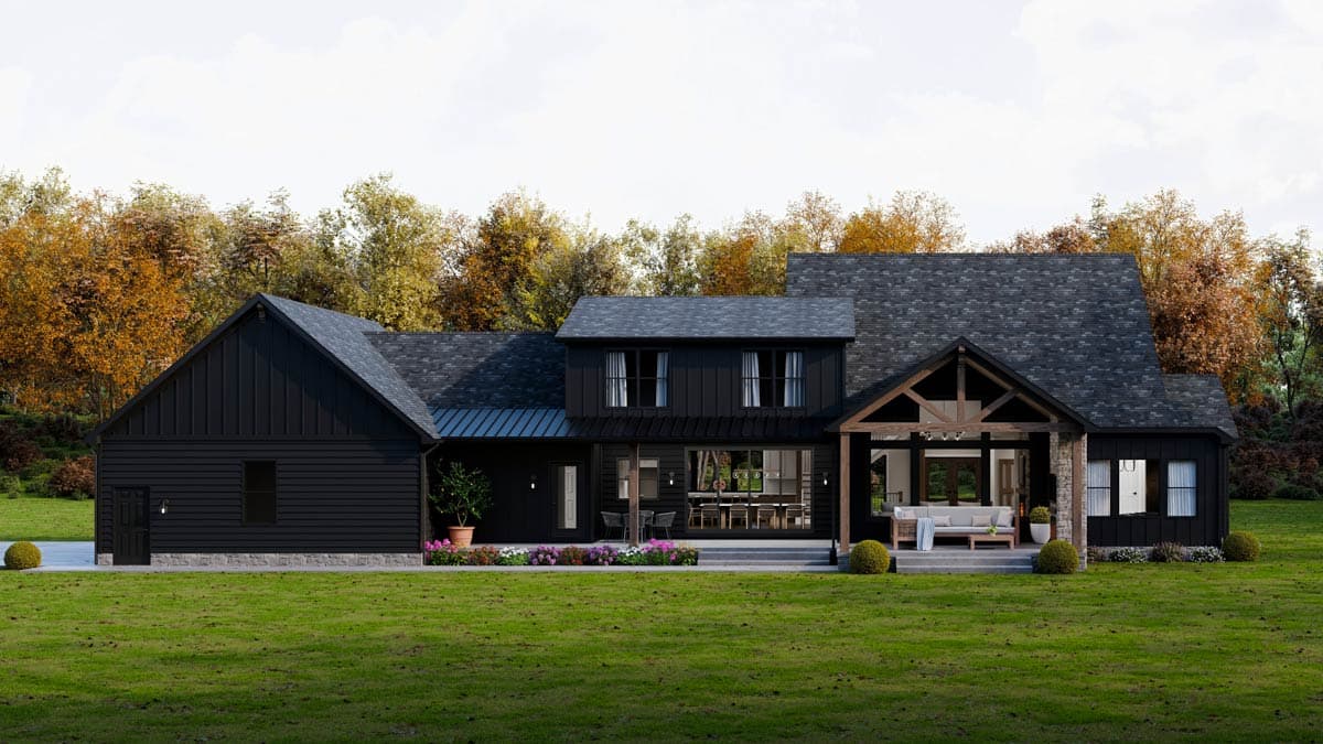 Modern black farmhouse with a covered porch, large windows, and an open layout, set against a backdrop of fall foliage.
