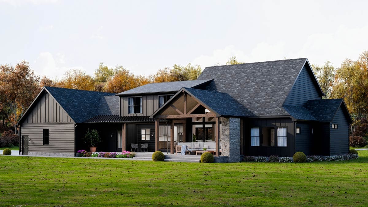 A modern, two-story house with dark siding and a covered porch. The house is set on a well-manicured lawn with fall foliage in the background.